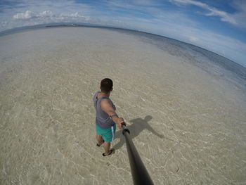 Rear view of man on beach against sky