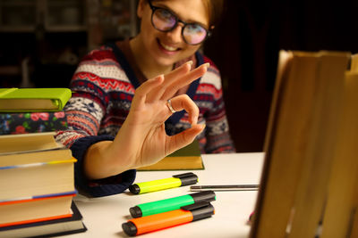 Young smiling woman in glasses study at night. millennial student posing and showing sign okay, ok. 