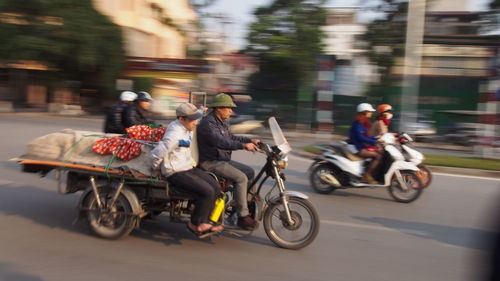 People riding tricycle and motorcycles on road