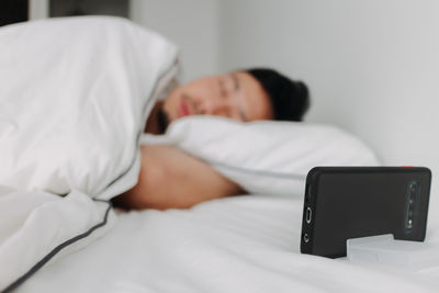Woman using mobile phone while lying on bed at home
