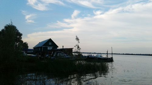 Stilt house by sea against sky