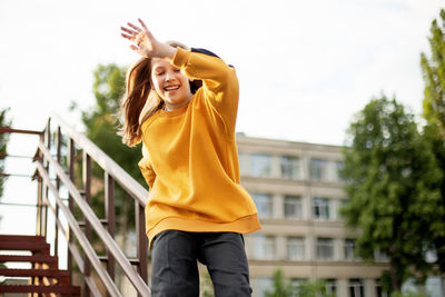 Portrait of young woman standing against building