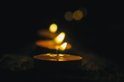 Close-up of lit tea light candles in dark