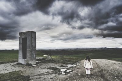 Rear view of woman standing on land against sky