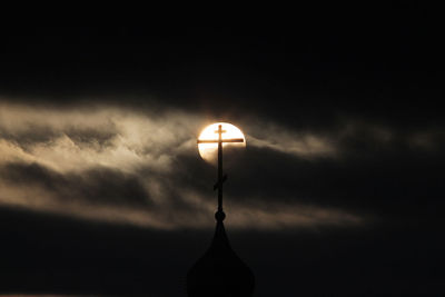 Silhouette light against cloudy sky at night