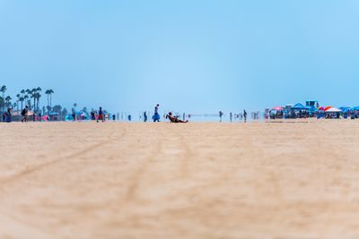 People at beach against clear sky