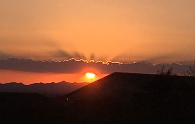 Scenic view of silhouette mountains against romantic sky at sunset