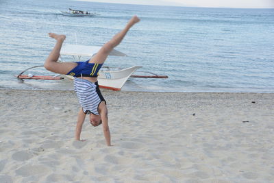 Man practicing handstand on shore at beach