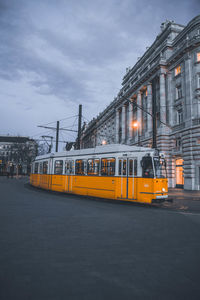 Cars on illuminated street in city against sky