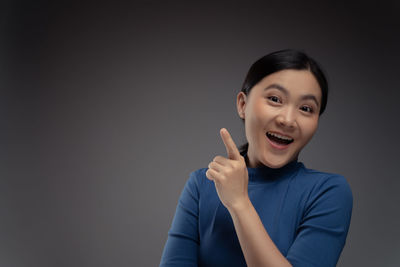 Portrait of smiling young woman against black background