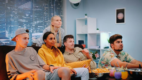 Portrait of smiling friends sitting on sofa at home
