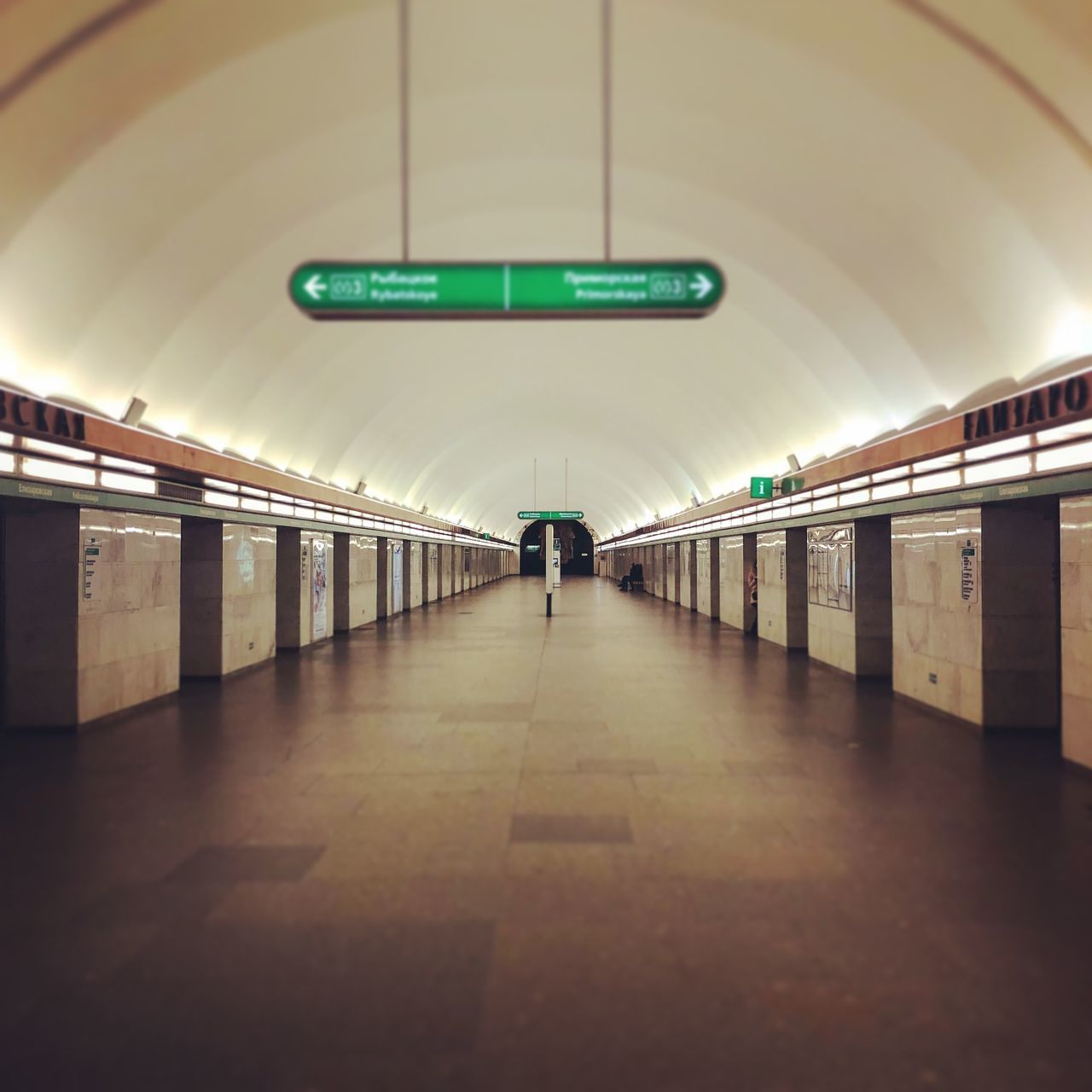 REAR VIEW OF MAN WALKING IN ILLUMINATED UNDERGROUND CORRIDOR