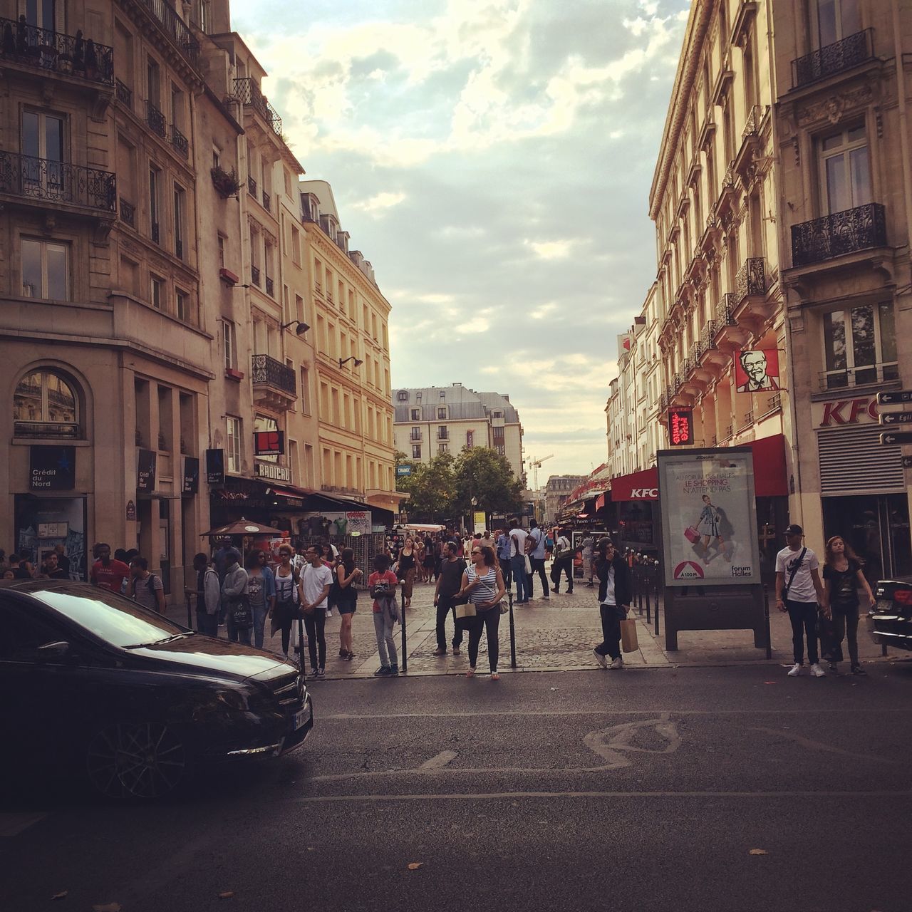 architecture, building exterior, built structure, large group of people, city, street, sky, men, person, city life, walking, building, cloud - sky, transportation, lifestyles, city street, road, incidental people, cloud