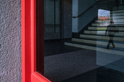 Man walking on road by window in city