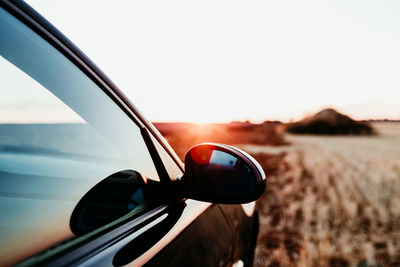 Close-up of side-view mirror against sky