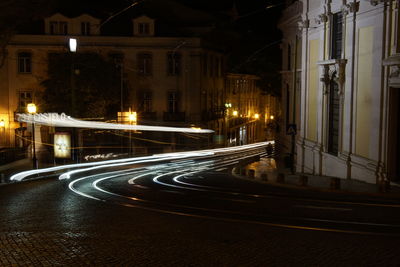 Light trails on road amidst buildings in city at night