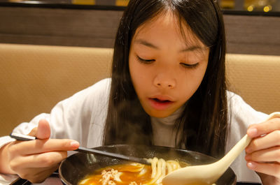 Close-up of girl eating noodles with chopsticks at restaurant 