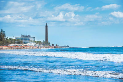 Lighthouse by sea against sky
