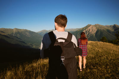 Rear view of friends standing on mountain against sky