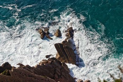 High angle view of waves on rock in sea