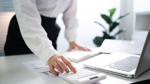 Midsection of businessman using laptop at office