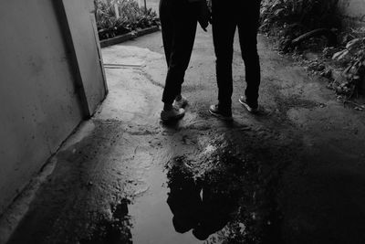 Low section of men standing on wet road