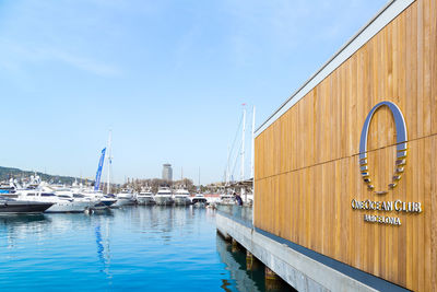 Sailboats moored at harbor against sky