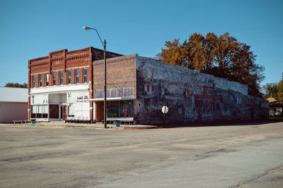 Exterior of houses in front of road against clear blue sky