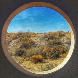 Close-up of landscape against sky seen through window