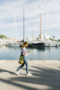 Young woman text messaging on smart phone while walking at seaside