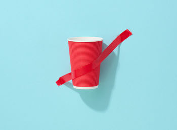 Red cardboard cup glued with red sticky tape to the blue background