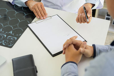 Midsection of man holding paper with text on table