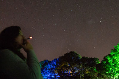 Silhouette woman holding plants against sky at night