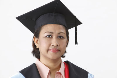 Woman in graduation gown against white background