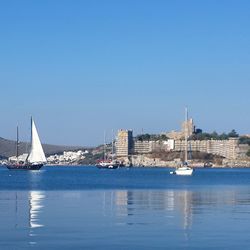 Boats sailing in sea against clear blue sky