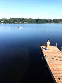 Woman standing on boat sailing in lake against clear sky