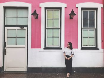 Full length of woman standing against house