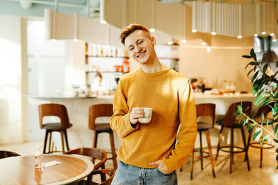 Portrait of smiling young man standing on chair