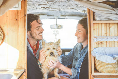 Happy couple with dog sitting in caravan