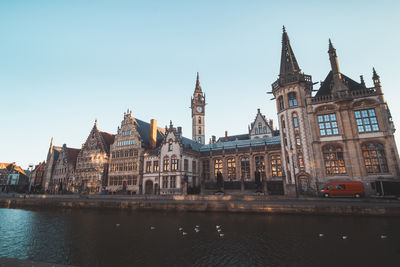 Buildings by river against sky