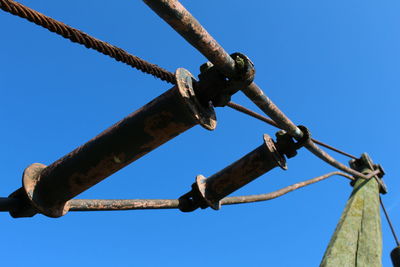 Low angle view of rusty metallic cable on pole