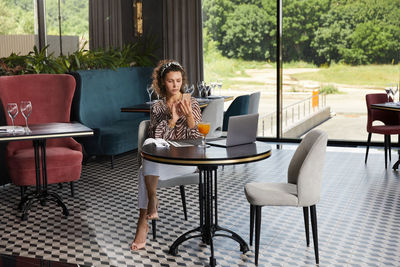 Woman using mobile phone while sitting at cafe