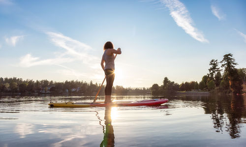 Man standing on boat in lake against sky