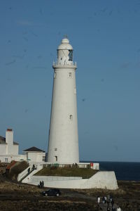 Lighthouse by sea against sky