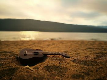 Guitar on beach against sky