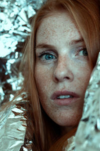 Close-up portrait of young woman with freckles on face