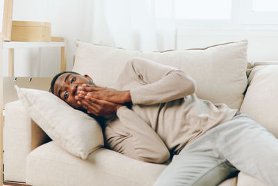 Low section of woman sitting on sofa at home