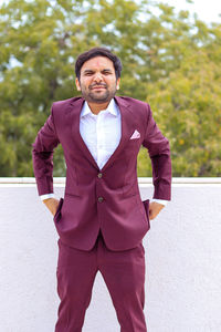 Portrait of young man standing against wall