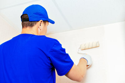 Rear view of man wearing hat against wall