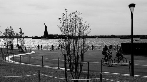 People on bicycle by tree against sky